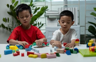 Fototapete Lego Two young children playing with colorful building blocks at home, encouraging creativity, imagination, fine motor skills, problem solving, early childhood education, teamwork, and playful learning.  © Father_Studio