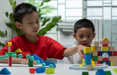 Fototapete Lego Young children building colorful toy blocks and a wooden castle at home, promoting teamwork, creativity, concentration, problem solving, early childhood education, and imaginative learning.  © Father_Studio