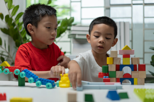 Two young children playing with colorful building blocks at home, inspiring teamwork, creativity, communication, problem solving, early childhood education, cognitive development, and imaginative play