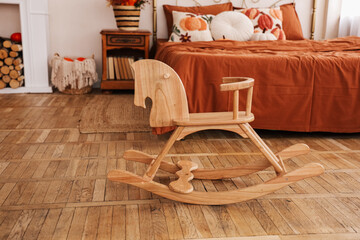 Wooden rocking horse placed in a cozy room with a bed and decorations during daytime © ir1ska