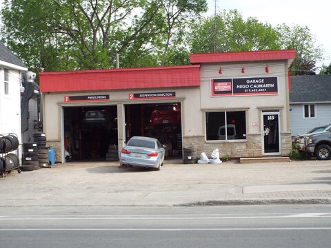 Gatineau,Quebec, Canada &ndash; June 4, 2026: The "Garage Hugo Caumartin" auto repair shop features bilingual pneus freins and suspension direction service bay signs at 143 Rue Principale.