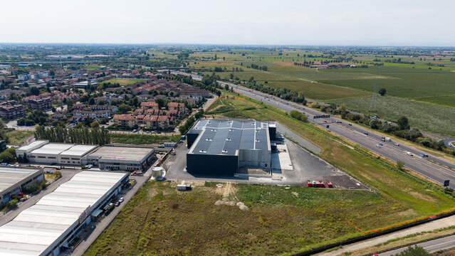 Drone perspective of a refrigerated logistics hub equipped with photovoltaic panels and industrial ventilation, supporting sustainable food storage and distribution in northern Italy.