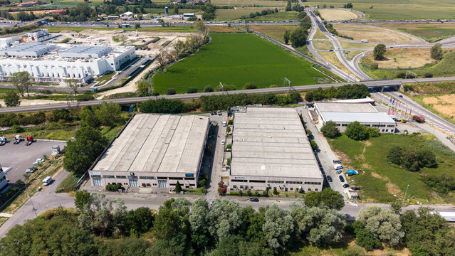 Top view of a logistics hub Melegnano, Italy, showing industrial buildings equipped with rooftop solar systems and modern commercial infrastructure.