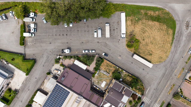 Aerial View of a Truck Stop: An overhead drone shot reveals a busy truck stop with parked semi-trailers, cars, and buildings, showcasing industrial infrastructure and logistics. Melegnano, Milan, Ital