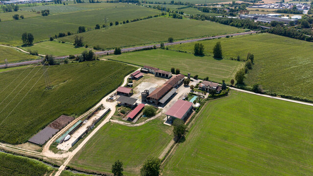 Aerial View of a Rural Farm Complex: An expansive drone shot captures a sprawling farm, complete with various agricultural buildings, Tavazzano con Villavesco, Lodi, Italy