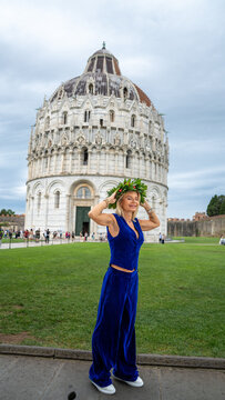 University graduate in Pisa wearing traditional laurel crown strolling near the Tower and Baptistery
