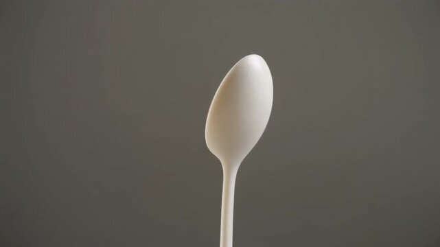 Single White Plastic Spoon Isolated on Neutral Background with Soft Lighting and Minimalist Viewpoint for Kitchen and Dining Concepts