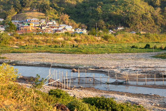 Dried Riverbed with Fishing Structures in Rural Landscape