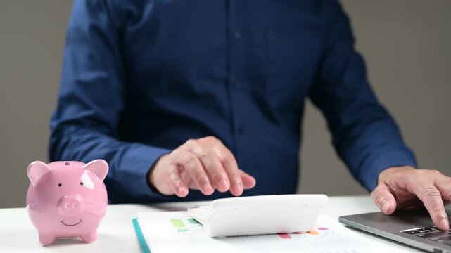 Professional male accountant analyzing financial spreadsheet documents, calculating corporate tax expenses, reviewing quarterly budget reports sitting inside office workspace desk.