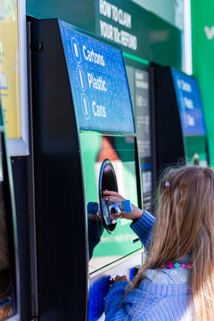 child returning plastic bottle for recycling at return and earn collection point in Australia