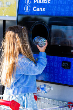 child returning plastic bottle for recycling at return and earn collection point in Australia