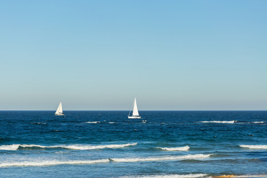 Sailboat on sunlit day sailing out of Newcastle Harbour