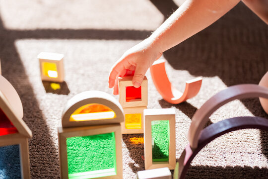 Light shining through colourful toy blocks set up by child on sunlit floor
