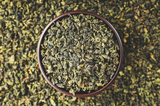Premium Tieguanyin in dark wooden bowl on green tea pattern background