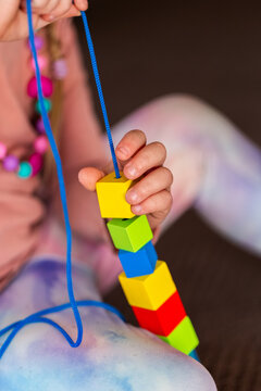 preschooler doing beading threading activity with thread and wood bead