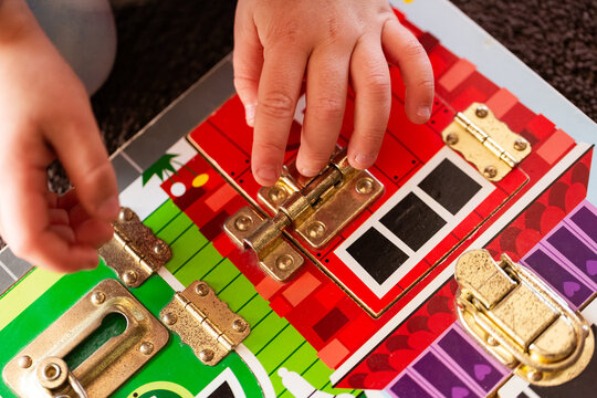 child working on colourful lock puzzle board on floor