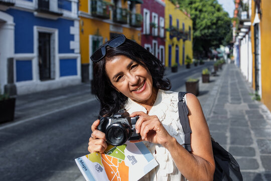 senior latin woman traveling and holding a tourist map in Mexico Latin America, hispanic mature adult or middle age female tourist in colonial city 