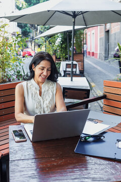 senior latin woman using laptop and having fun outdoors in terrace in Mexico Latin America, mexican female working with computer  