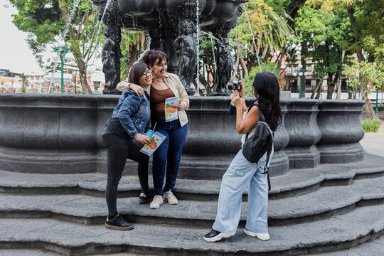 senior women latinas friends traveling and holding a tourist map in Mexico downtown in Latin America, hispanic middle age people tourist in fountain in colonial city 