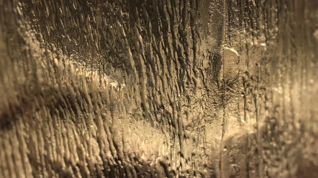 Macro view of a golden crystal surface with rippled texture and soft reflections. Concept design, luxury, branding, wallpaper, advertising, art, and creative background use.