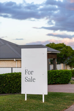 for sale sign outside home with neat green hedges