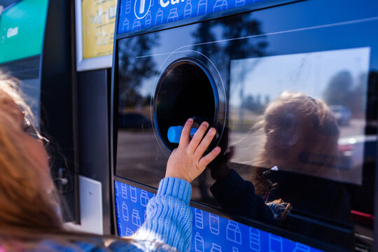 child returning plastic bottle for recycling at return and earn collection point in Australia