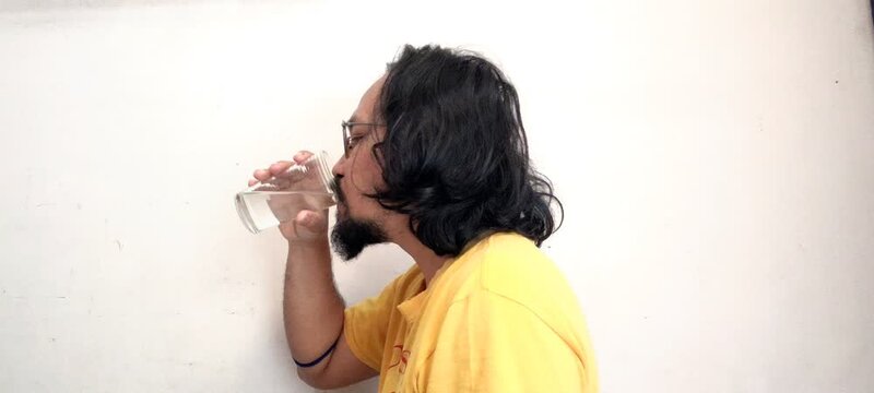 Man with long hair drinking water from a glass.