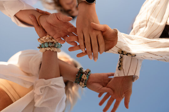 Hands connection teamwork, diverse people joining together in unity under a clear blue sky, symbolizing collaboration community and partnership.