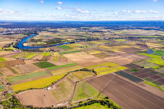 Aerial view of a patchwork farmland beside the meandering river