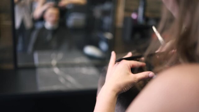 A skilled barber focuses intently as he uses clippers to shape a man's fresh haircut in a lively salon setting filled with the sounds of chatter and buzzing tools in the afternoon light.