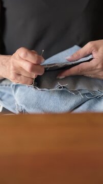 Hand sewing denim jeans hem with thimble scissors pins vertical- Rec709 Color Graded
