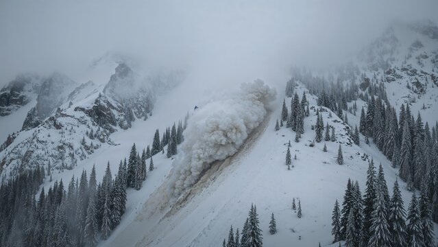 Snow avalanche on mountain slope with trees, in snowy winter landscape. Mountain and nature scene, natural disaster, winter weather.