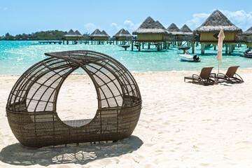 Fototapeta premium Wicker beach cabana overlooking turquoise lagoon and overwater resort villas