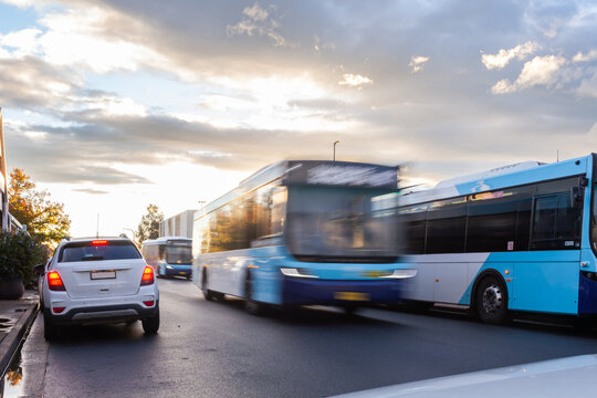 Motion blur of public transport busses traveling down road in Singleton at sunset