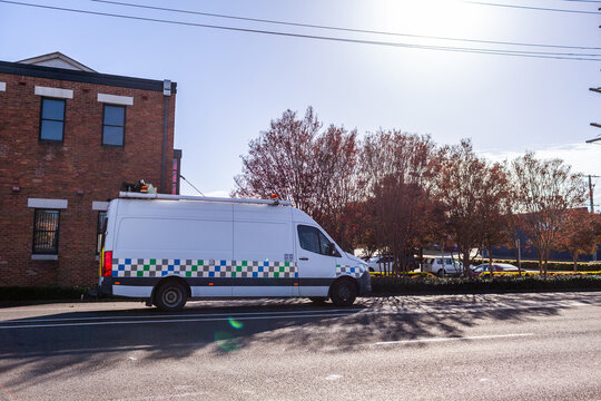 Van passing Autumn trees alongside street in town of Cessnock