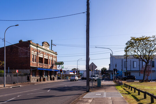 Sunlit streetscape scene in Cessnock with old building  and cars waiting at lights