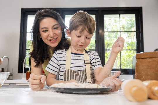Woman child baking kitchen flour dough smile apron family home woman and child baking with flour and dough bright kitchen, smiling together during home cooking activity with apron, window