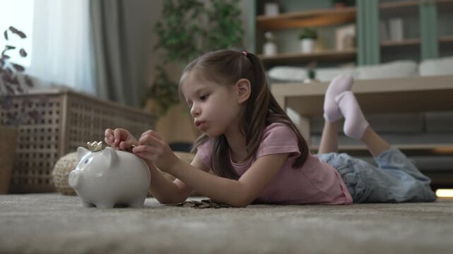 Little girl inserting coins into piggy bank