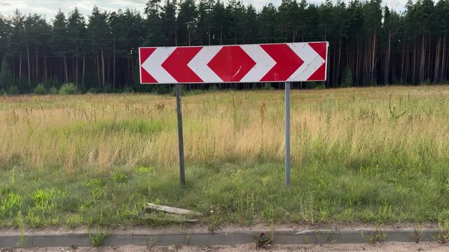 Traffic sign indicating a T-intersection or road fork where movement is only left or right, in a grassy field. Road safety, traffic control