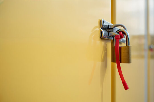 Padlock and security seal on a yellow metal cabinet door. Space for text.