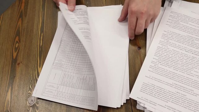 the office manager reviews and sorts through the documents in the stacks of papers, and pushes them off the desk