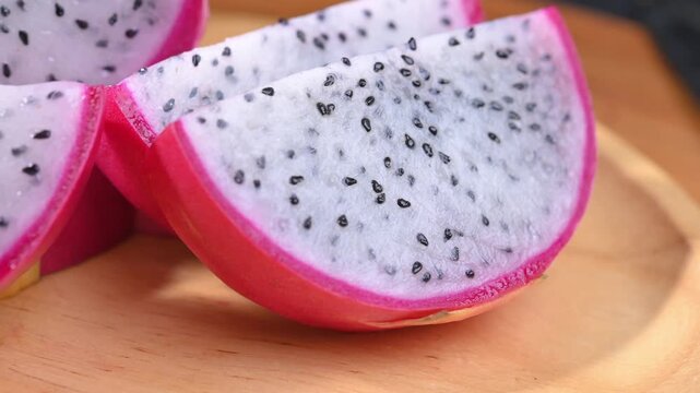Fresh dragon fruits displayed on a rustic wooden plate, highlighting their vibrant pink skin and natural freshness. A healthy tropical fruit rich in fiber, antioxidants, and vitamin C, perfect for con