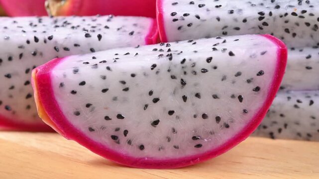 Fresh dragon fruits displayed on a rustic wooden plate, highlighting their vibrant pink skin and natural freshness. A healthy tropical fruit rich in fiber, antioxidants, and vitamin C, perfect for con