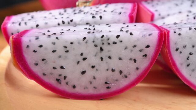 Fresh dragon fruits displayed on a rustic wooden plate, highlighting their vibrant pink skin and natural freshness. A healthy tropical fruit rich in fiber, antioxidants, and vitamin C, perfect for con