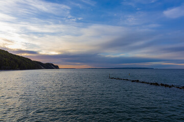 Obraz premium Twilight over Baltic coastline with dark wooded cliffs and serene sea waters