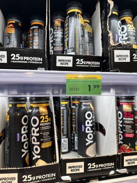 Danone YoPRO high-protein yogurt drinks in black bottles displayed with a &euro;1.99 price tag on a refrigerated supermarket shelf, showing branded dairy retail packaging, 2 April 2026, Lissabon, Portugal