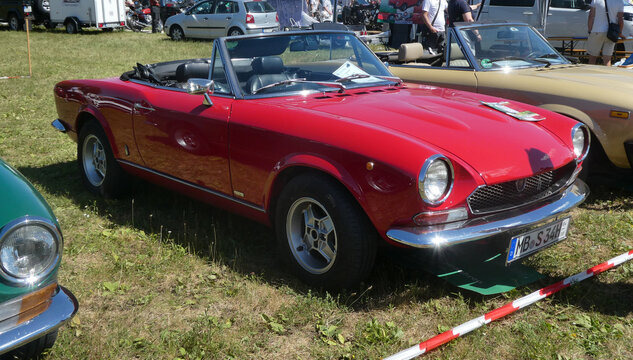 Garching near Munich, Germany - Old Timers Show: vintage red Fiat 124 spider BS1 sport car lateral view