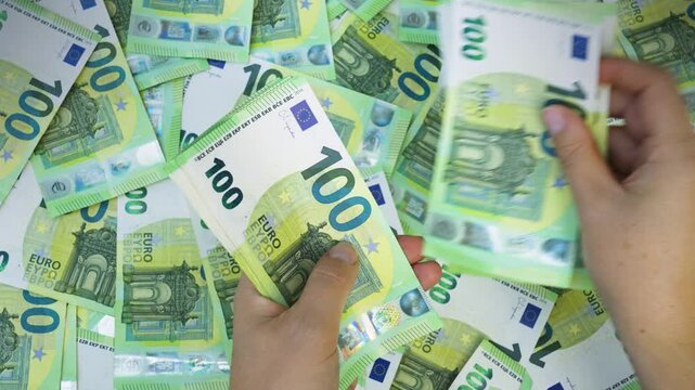 Macro close-up of hands counting numerous 100-euro banknotes, focusing on fine details. 4K video.