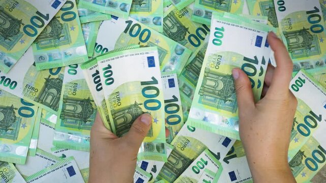 Macro close-up of hands counting numerous 100-euro banknotes, focusing on fine details. 4K video.