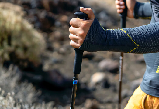 A man is hiking, running with trekking poles in the mountains.